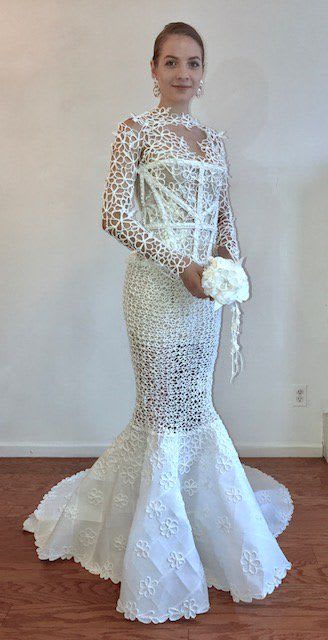 This 70s-vibe August Manzanares gown is covered in floral netting detail and features a meticulously crafted sheer bodice and sleeves with a solid skirt that flares out in true trumpet style at the bottom.