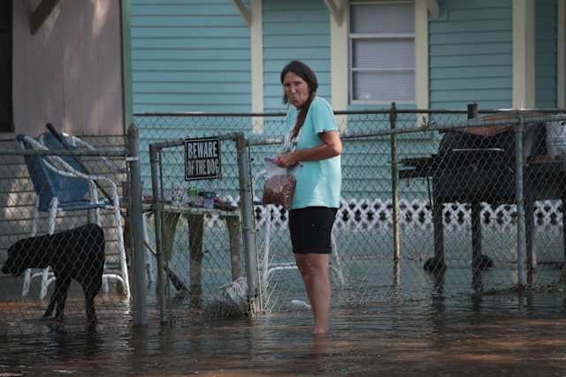 With no home left to defend, the beware of the dog sign is oddly out of place as this woman prepares to feed her pet.